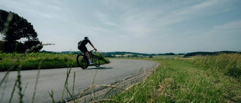 A cyclist rounding a bend on a quiet country road.